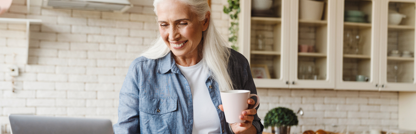 Woman smiling with coffee and open computer